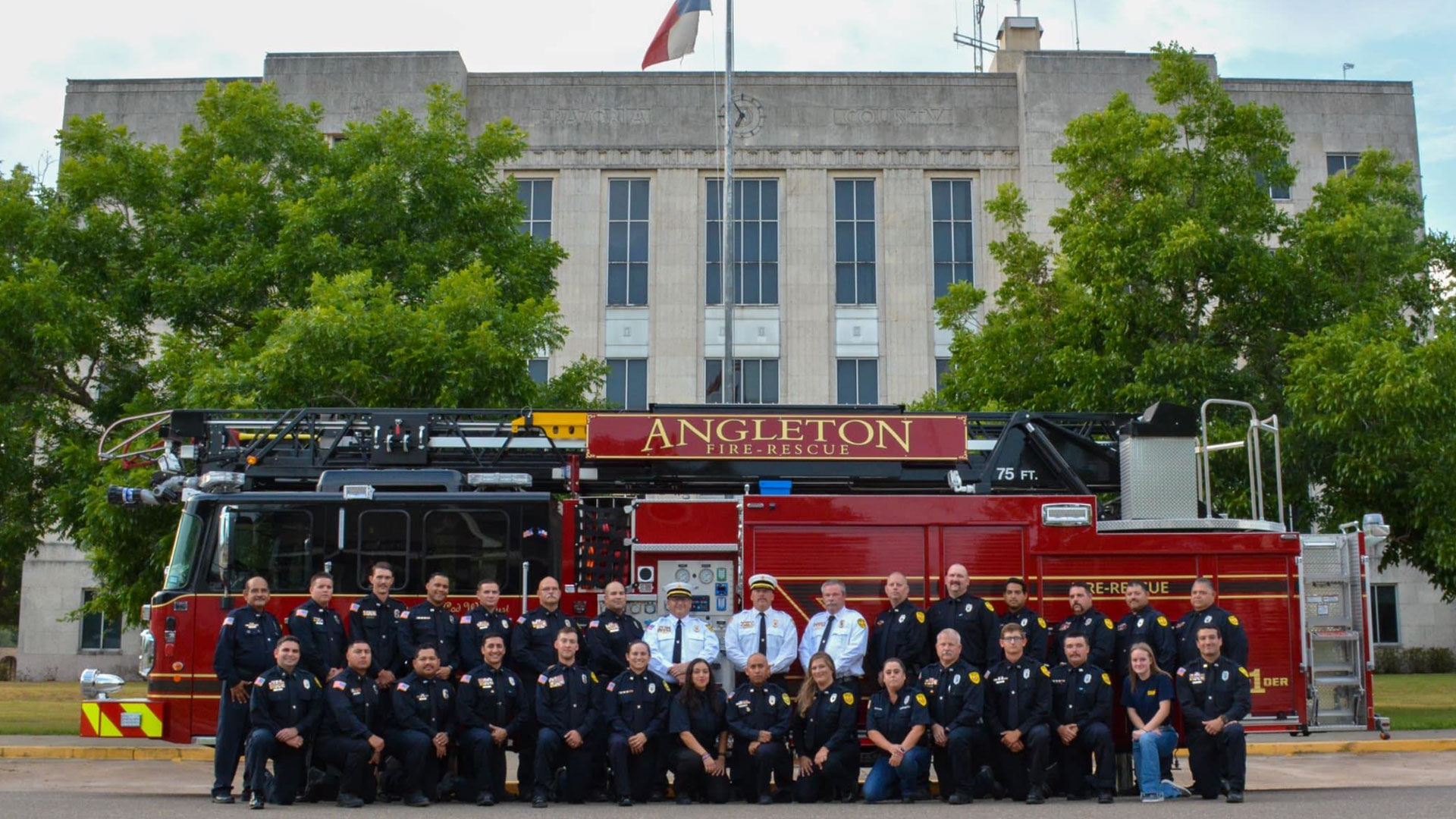 Angleton Firefighters with Firetruck at City Hall Members of the Angleton Volunteer Fire Department posing about a firetruck in front of city hall.