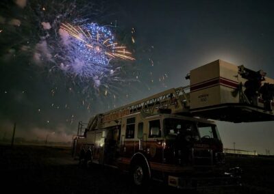 An Angleton Volunteer Fire Department firetruck with a fireworks show in the background.