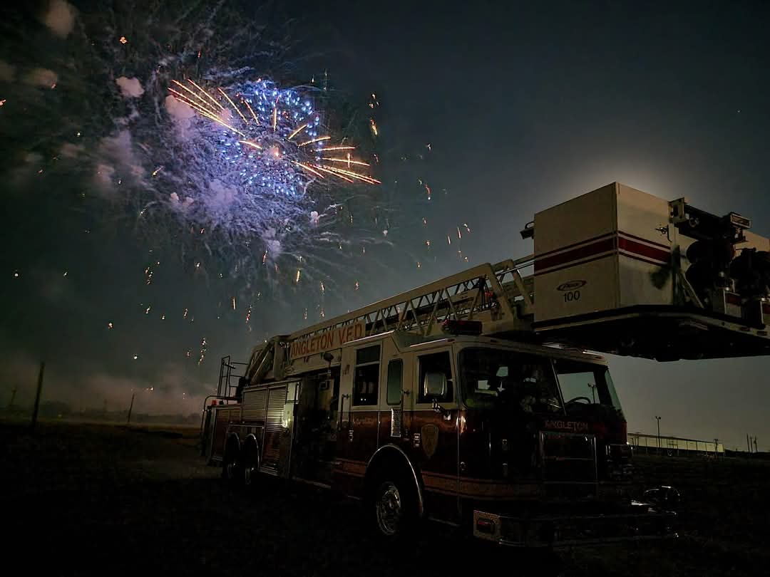 An Angleton Volunteer Fire Department firetruck with a fireworks show in the background.