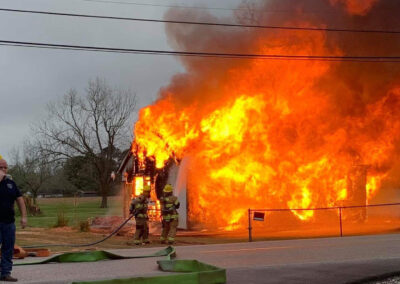 A fire destroys a house while firefighters spray it with water.