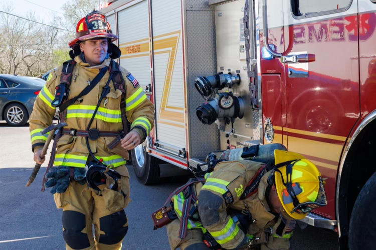 Two firefighters beside firetruck Two career firemen prepare to respond to a fire beside a firetruck.